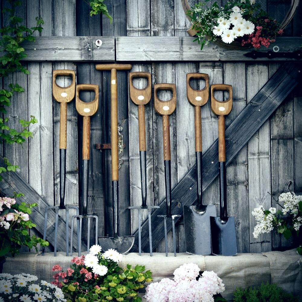 Gartenwerkzeuge stehen am Gartenzaun